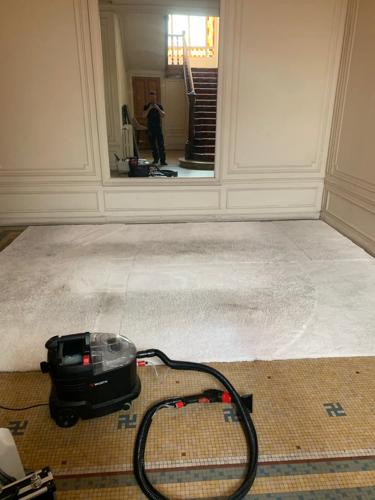 Matériel de nettoyage et tapis clair dans une entrée
